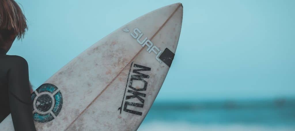 Photo of a man holding a surfboard and looking at the sea