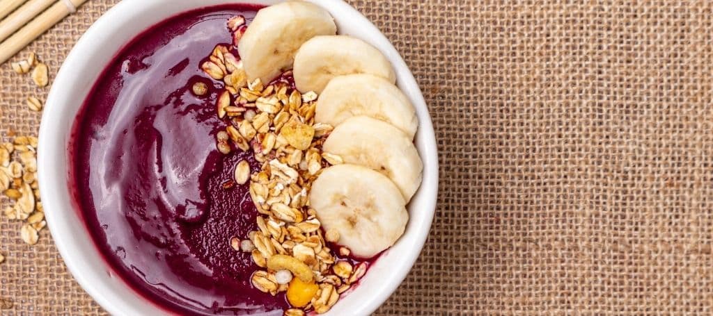açai bowl with banana and granola on a table