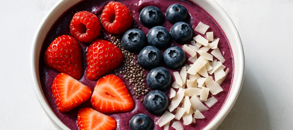 Close-up of an Amazon açaí TBS smoothie bowl topped with strawberries, blueberries, chia seeds and coconut flakes.
