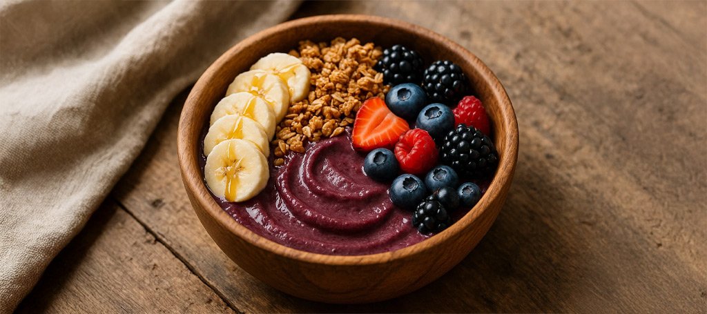 Rustic wooden bowl filled with Amazon açaí TBS, banana slices, crunchy granola and honey drizzle.